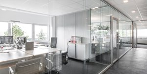 Eine Glaswand sorgt innen für lichtdurchflutete Büroräume in moderner Optik